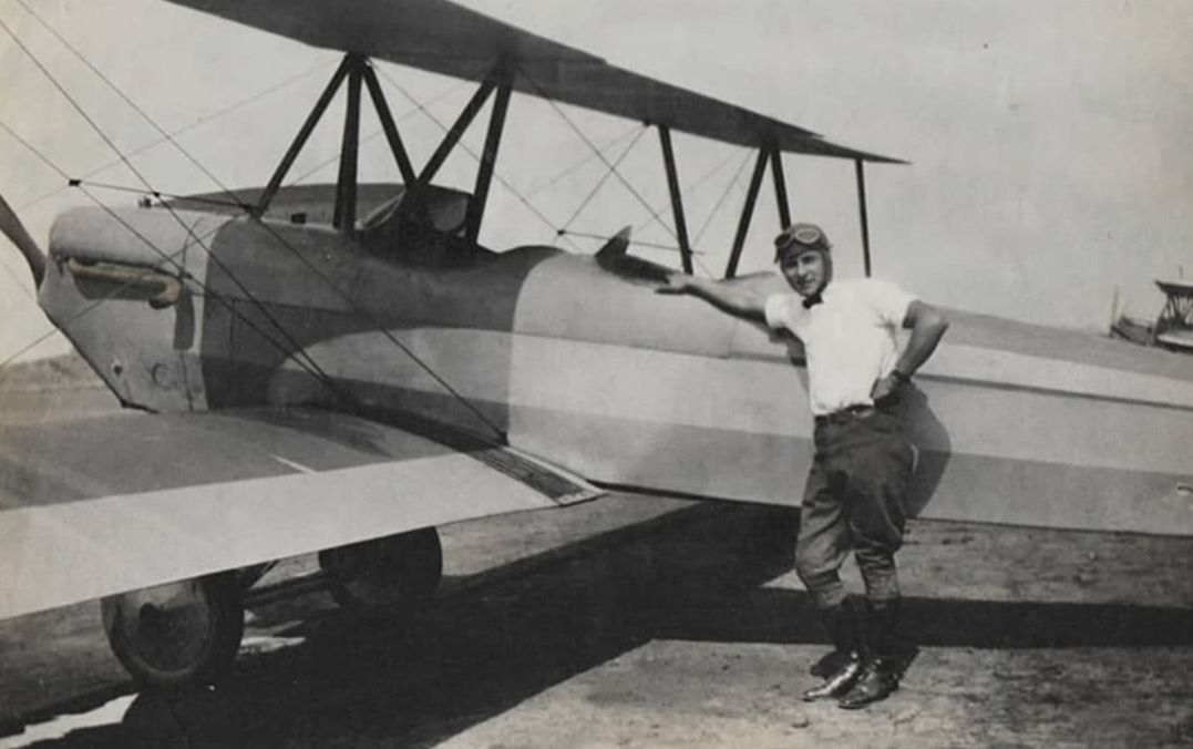 A Bresnik aviator standing beside a biplane, 1929